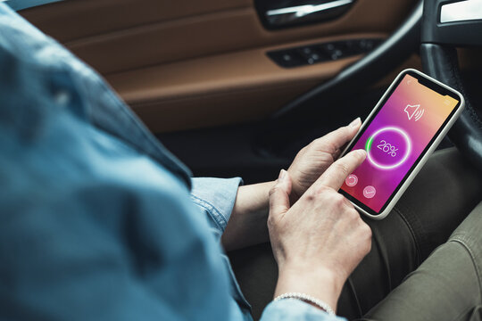 Woman adjusting volume through smart phone while sitting in car