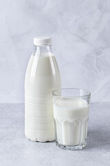 Full bottle and glass of milk on a gray table background. Healthy food, a source of calcium. Cooking ingredient, drink.