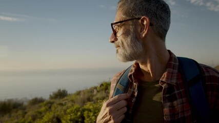 Mature hiker looking at the view while standing on a coastal hilltop