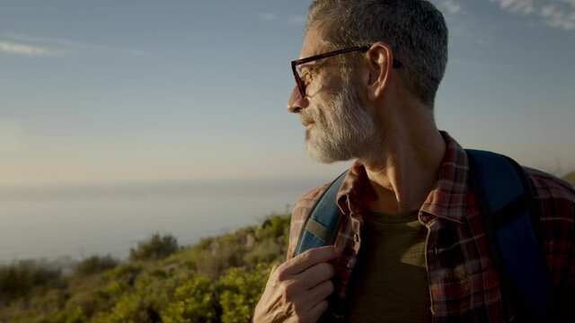 Mature hiker looking at the view while standing on a coastal hilltop
