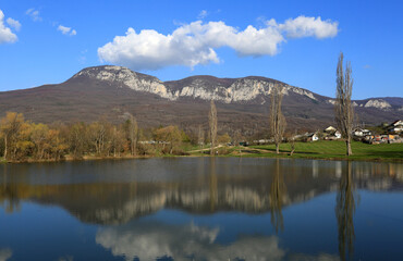 Fototapeta na wymiar Spring landscape in the Crimea. Mountains and clouds in the blue sky reflected in the lake in the countryside