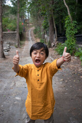 a boy laughs and shows thumbs up at the camera