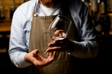 male hands gently hold empty clear wine goblet glass.