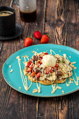 Heart waffle with banana and strawberry with gummy candy and ice cream on it.