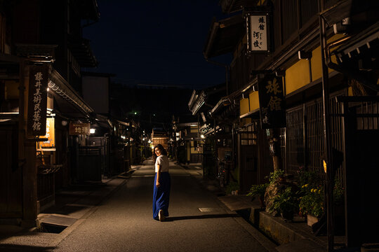 Japan, Takayama, Lone Woman Walking Between Rows Of Traditional Japanese Houses At Night