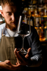 Front view on beautiful clean empty transparent wine goblet in male hand.