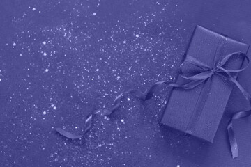 Trendy Color of Year 2022 Very Peri. Purpule gift box with bow on trendy color background with...