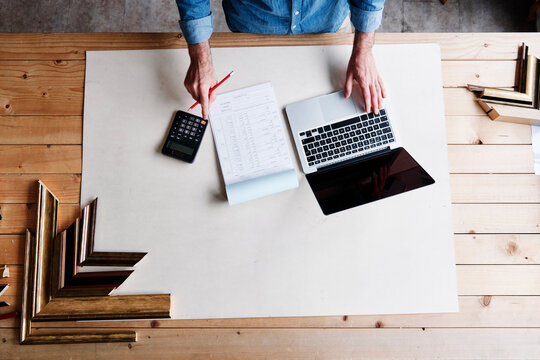 Mature male store owner calculating financial bill while standing at table