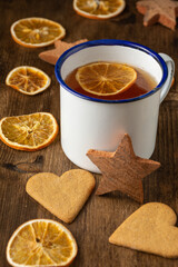 Top view of cup of tea with orange, on table with gingerbread cookies and orange slices, vertical