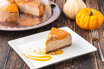 Delicious pumpkin cheesecake in white plate on wooden table