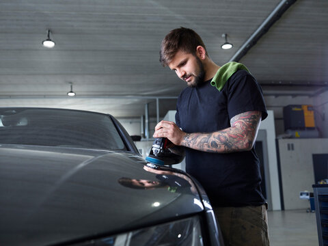 Technician polishing car with equipment at garage