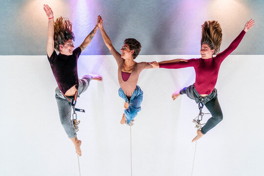 Smiling dancer holding hands while hanging on rope in dance studio