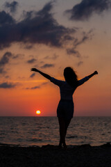 Fototapeta premium Happy young woman having fun with open hands at the sunset on sea.