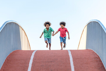 Boys with holding hands running on footbridge