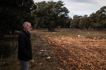 Fototapeta premium Adult man in winter clothes in rural area with trees