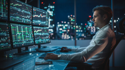 Naklejka premium Financial Analyst Working on a Computer with Multi-Monitor Workstation with Real-Time Stocks, Commodities and Exchange Market Charts. Businessman Works in Investment Bank Downtown Office at Night.