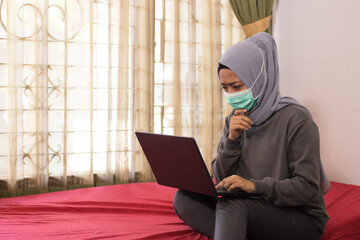 Asian women wearing hijabs wearing masks are working from home