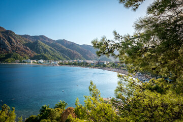 Summer landscape on the Mediterranean coast in Turkey. View of Icmeler beach, bay and mountains through pine branches