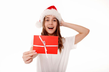 Happy young teenager girl in santa Claus red hat holds red gift certificate on white background. People lifestyle Christmas holidays concept.
