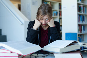 young woman studying in a library, bored or saturated and worried