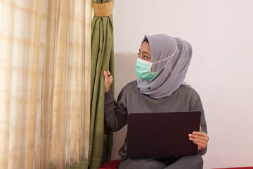 Asian women wearing hijabs wearing masks are working from home