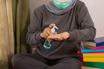 Asian women wearing hijab with masks are wearing hand sanitizers and working from home