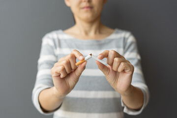 Portrait young woman holding broken cigarette in hands. Happy female quitting refusing smoking...