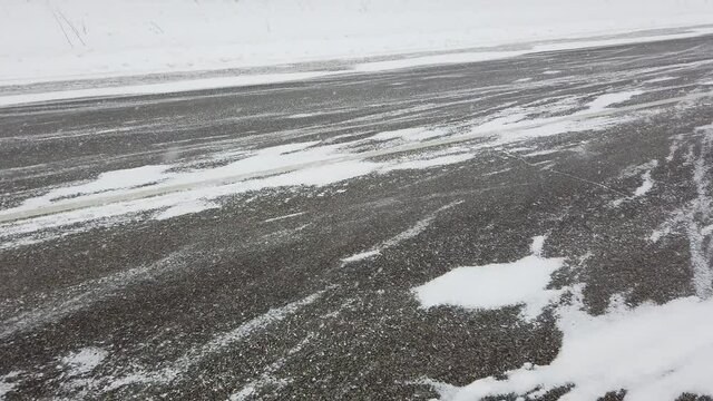 Steadicam close up shot of siberian intercity highway. Strong wind and heavy snowstorm in evening. Snowed field is behind the road