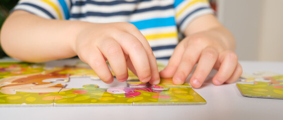 The child's hands close-up put together a picture of puzzles