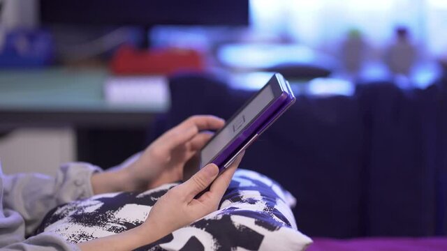 Young beautiful caucasian woman sitting on bed at home with e-book reader