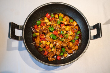 Delicious fried chicken with chili in an iron pot
