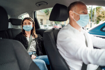 Taxi driver in a mask with a client on the back seat wearing mask