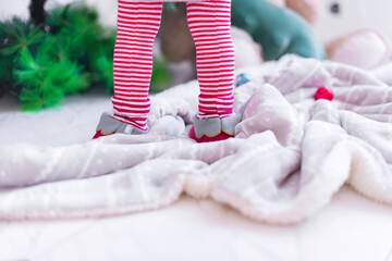 Little elf's legs near the Christmas tree. Festive decorating at home