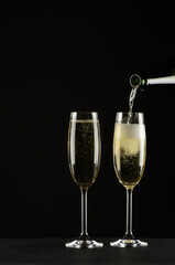 Pouring champagne into a glass on black background