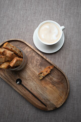 Fresh baked cookies biscotti on a wooden tray with cappuccino .