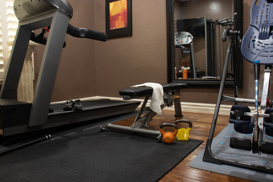 Home gym in spare bedroom with a treadmill, bench, and weights