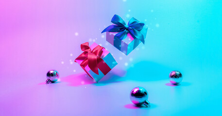 Neon merry Christmas winter background. Xmas gift box with shine lights. Holiday gifts, decoration bauble ball on neon abstract gradient backdrop. New year banner.