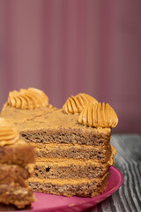 Banana cake with butter cream. Lies on a plate, cut into pieces. On black pine boards. Close-up shot.