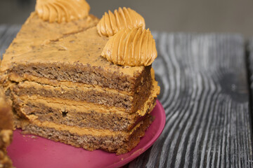 Banana cake with butter cream. Lies on a plate, cut into pieces. On black pine boards. Close-up shot.