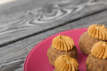 Banana cakes with butter cream. Lie on a plate. On black pine boards. Close-up shot.