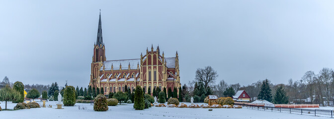 Neo-Gothic cathedral church in the town of Gervyaty in Belarus in the winter on dramatic sky background. Space for text.