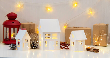 Childrens crafts made of white paper for Christmas, New Year. The decor of the houses is made of cardboard and garlands. Cozy atmosphere. Banner.