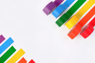 Multicolored rolls of rainbow-colored adhesive tape on the side on a white background.A set of bright sticky decorative ribbons for creativity, gift box packaging, for making postcards.Copyspace