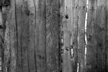 Wall made of uncutted weathered wood boards in black and white.