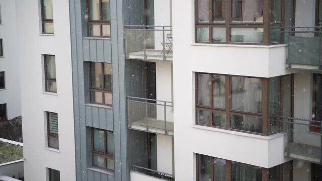 Slow-motion video of snow falling in the residential complex. Weather winter in the urban area. Snowing in front exterior modern condominium area.