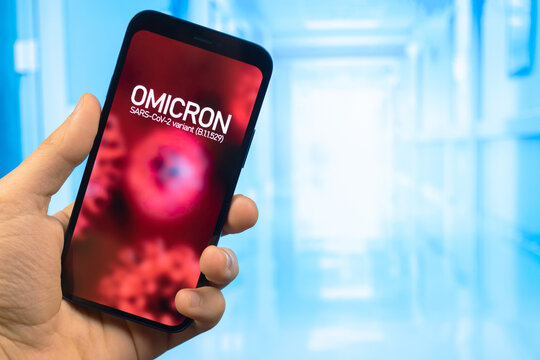 Omicron variant of coronavirus. Mobile phone with omicron text against hospital background. SARS-CoV-2, B.1.1.529. World epidemic concept photo