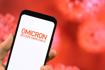 Omicron variant of coronavirus. Mobile phone with omicron text against virus germs background....