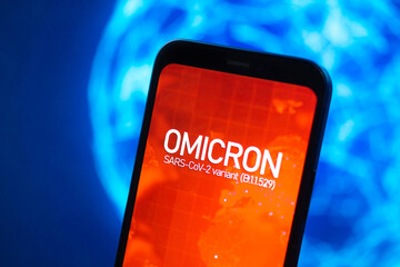 Omicron variant of coronavirus. Mobile phone with omicron text against earth planet global map...