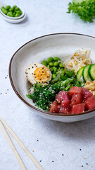 Poke salad with tuna and egg, lettuce, edamame beans, soy sprouts, cucumber, chukka seaweed, green onions, egg, honey and sesame sauce on white background
