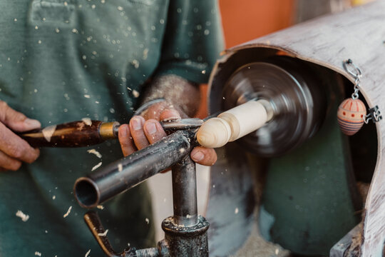 Midsection of male carpenter holding chisel while shaping wood at workshop